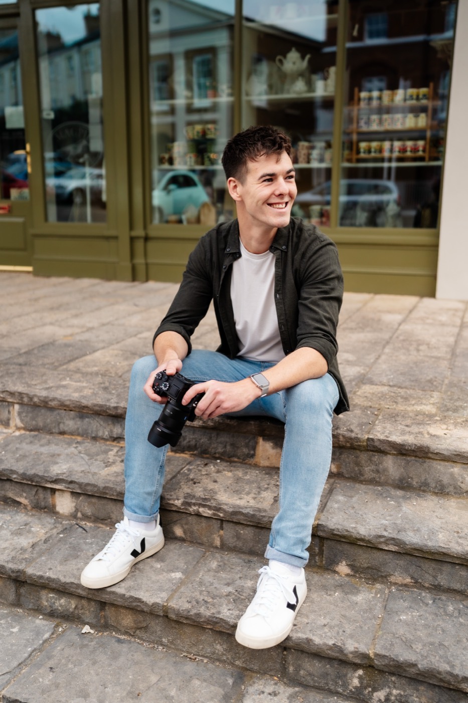 Arran Kenny sitting on steps with his camera